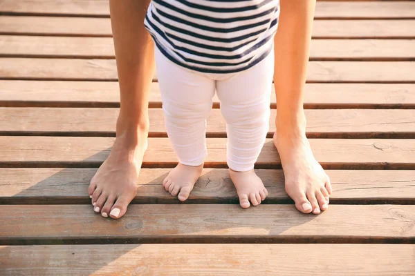 Anne küçük bebeğine dışarıda yürümeyi öğretiyor.