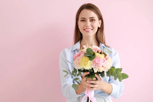 Belle jeune femme avec bouquet de fleurs d'oeillet sur fond de couleur — Photo