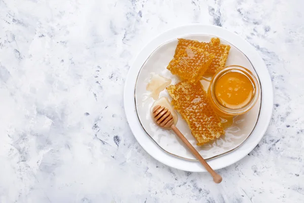 Tallrik med söt honung och kammar på bordet — Stockfoto