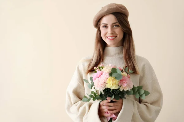 Beautiful young woman with bouquet of carnation flowers on light background — Stock Photo, Image