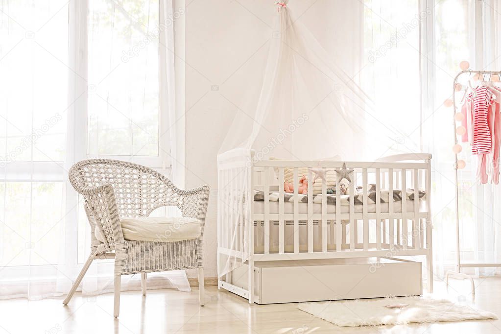 Interior of light modern baby room with crib