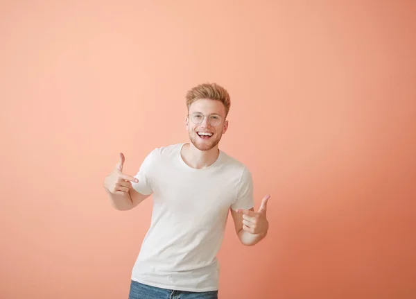 Mann zeigt auf sein T-Shirt vor farbigem Hintergrund — Stockfoto