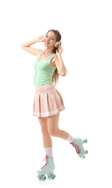 Beautiful young woman on roller skates listening to music against white background — Stock Photo, Image