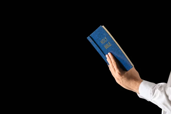 Religious man with Bible on dark background — Stock Photo, Image