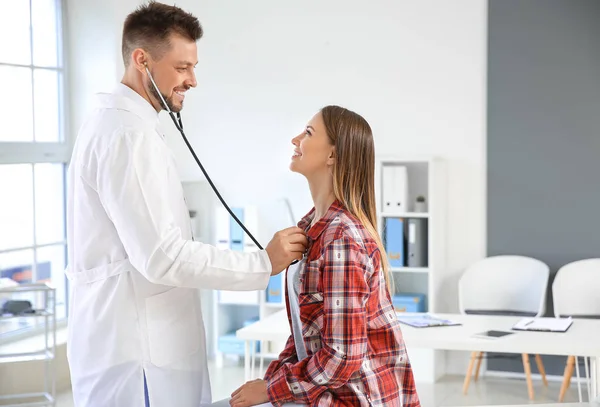Доктор слухає серцебиття жінки в клініці — стокове фото