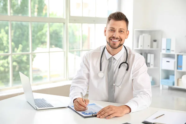 Mannelijke arts werkzaam aan tafel in kliniek — Stockfoto