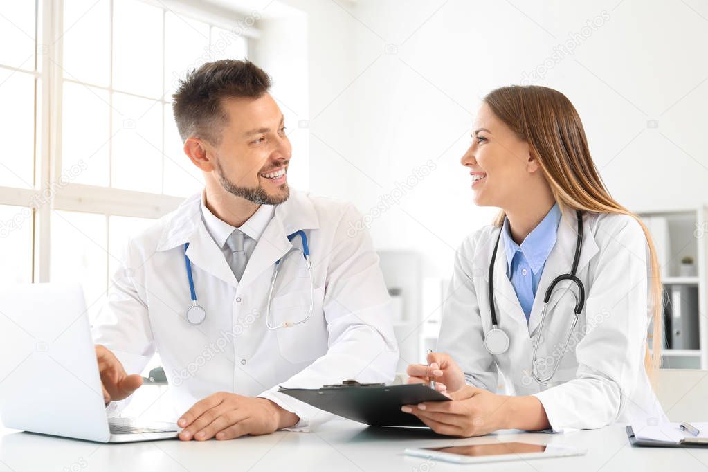 Male and female doctors working at table in clinic