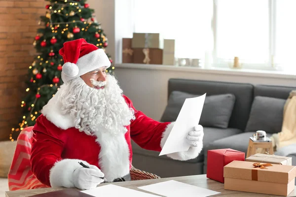 Санта Клаус читає список бажань у кімнаті, прикрашеній на Різдво. — стокове фото