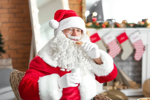 Święty Mikołaj picie mleka i jedzenie ciasteczek w pokoju udekorowane na Boże Narodzenie — Zdjęcie stockowe