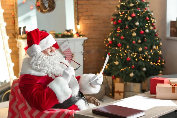 Noel Baba Noel için dekore edilmiş odada istek listesini okuyor.