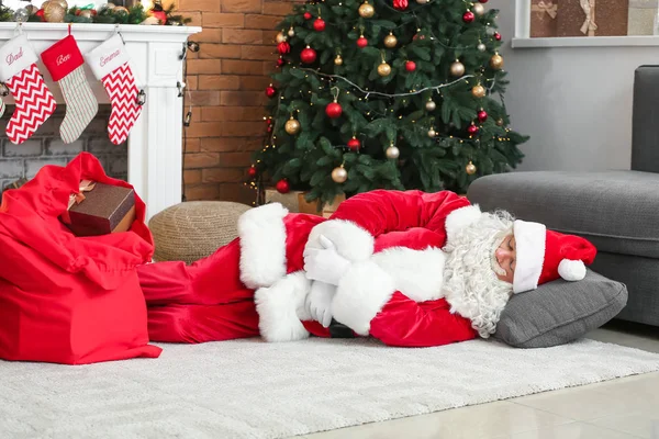 Κουρασμένος Άγιος Βασίλης κοιμάται στο πάτωμα στο δωμάτιο διακοσμημένο για τα Χριστούγεννα — Φωτογραφία Αρχείου