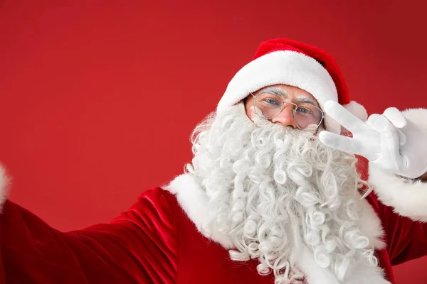 Portrait of Santa Claus taking selfie on color background — Stock Photo, Image