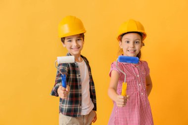 Kask ve renkli arka plan üzerinde boya silindirleri ile Sevimli küçük çocuklar