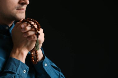 Dindar adam karanlık arka planda Tanrı 'ya dua ediyor.