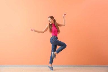 Güzel genç kadın renk duvarına karşı dans ediyor.