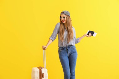 Renkli arka planda bavul, pasaport ve bilet ile mutlu genç kadın