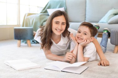 Küçük çocuk ve ablası evde kitap okuyor