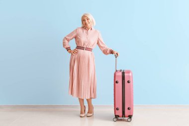 Renkli duvara karşı bagaj ile Olgun kadın