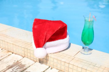 Tatil beldesinde yüzme havuzu kenarında Santa şapka ve kokteyl