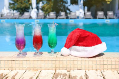 Tatil beldesinde yüzme havuzu kenarında Santa şapka ve kokteyller
