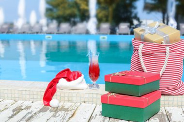 Noel Baba şapkası, kokteyl ve tatil beldesinde yüzme havuzu kenarında hediyeler