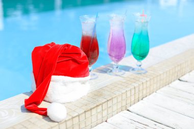 Tatil beldesinde yüzme havuzu kenarında Santa şapka ve kokteyller