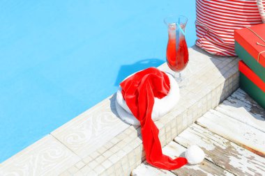 Tatil beldesinde yüzme havuzu kenarında Santa şapka ve kokteyl
