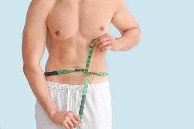 Renkli arka planda ölçüm bandı ile yakışıklı kaslı adam. Kilo kaybı kavramı