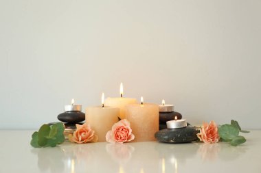 Işık arka planda spa taşları ve gül çiçekleri ile mum yakma