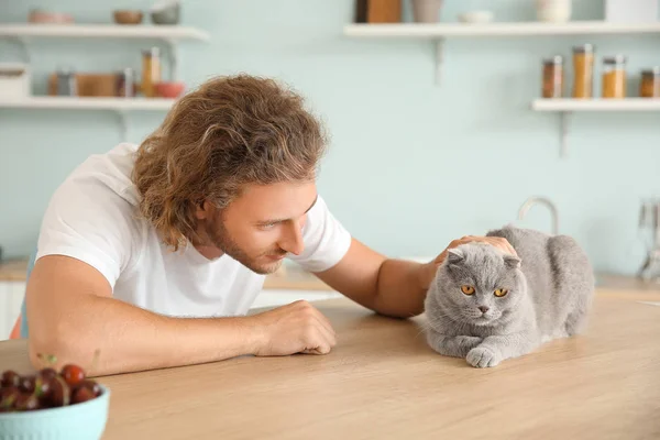 Man with cute funny cat at kitchen table — Stock Photo, Image