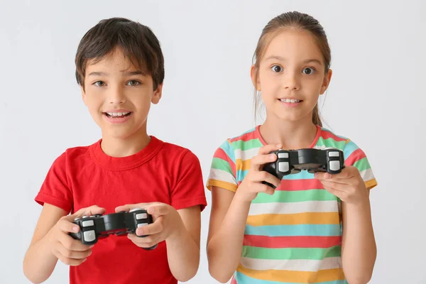 Enfants mignons jouant à des jeux vidéo sur fond clair — Photo