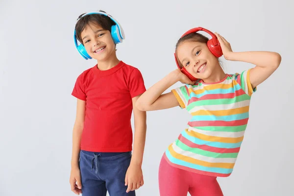 Lindos niños pequeños escuchando música sobre fondo claro —  Fotos de Stock