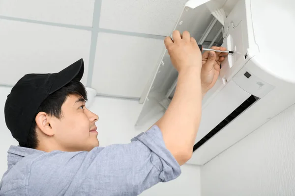 Eletricista reparação de ar condicionado dentro de casa — Fotografia de Stock