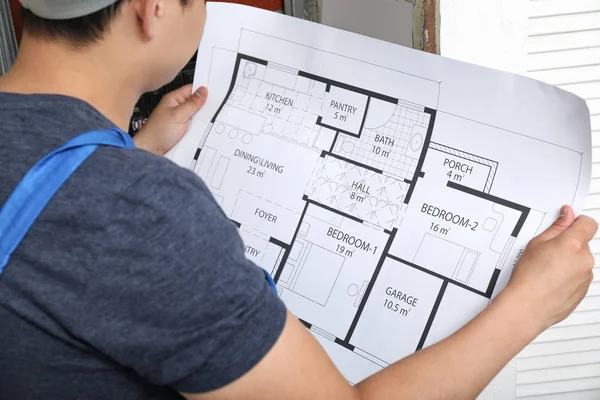 Electrician with plan of house indoors