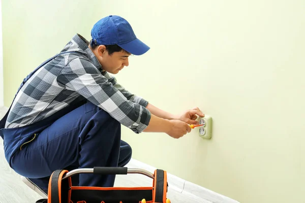 Eletricista reparando soquete no quarto — Fotografia de Stock