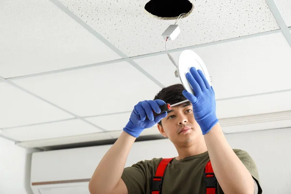 Electrician installing lamp on ceiling — Stock Photo, Image