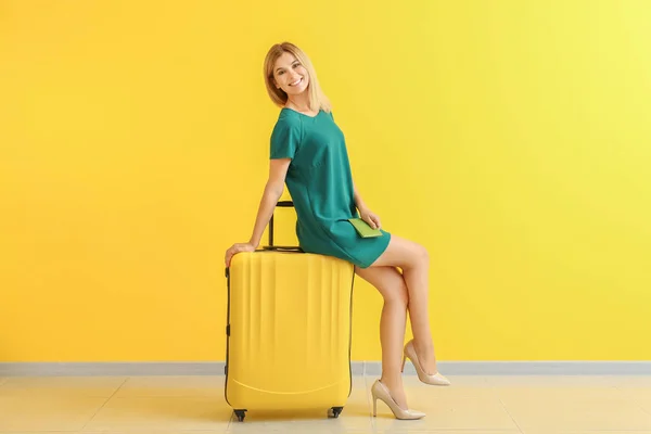 Happy beautiful woman with luggage and passport near color wall — Stock Photo, Image