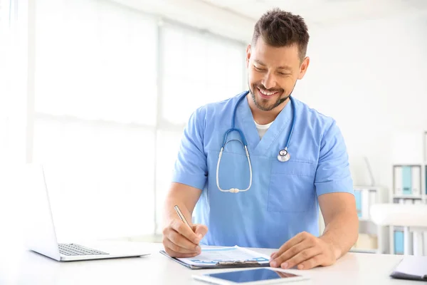 Mannelijke verpleegster werken aan tafel in kliniek — Stockfoto