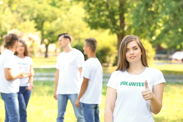 Portrait of female volunteer showing thumb-up outdoors — Stock Photo, Image