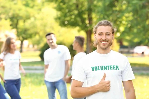 Portrait of male volunteer showing thumb-up outdoors — Stock Photo, Image