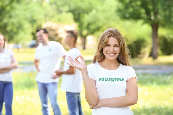 Retrato de una voluntaria mostrando OK al aire libre — Foto de Stock