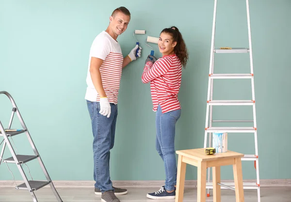 Счастливая молодая пара покрасила стену в своем новом доме — стоковое фото