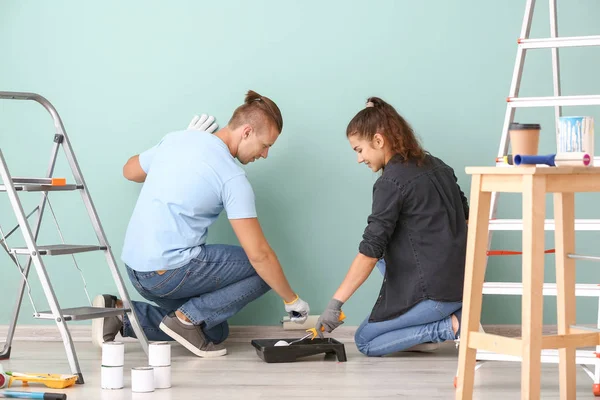 Счастливая молодая пара покрасила стену в своем новом доме — стоковое фото
