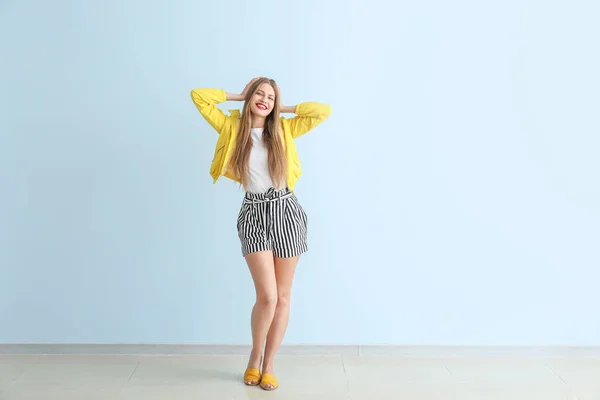 Happy young woman near color wall