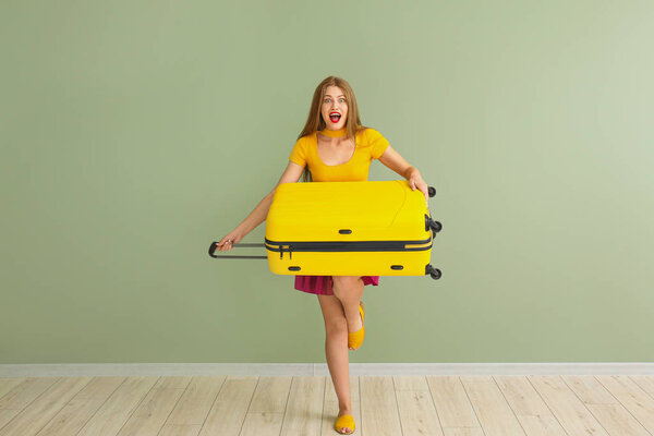 Счастливая молодая женщина с чемоданом на цветном фоне

