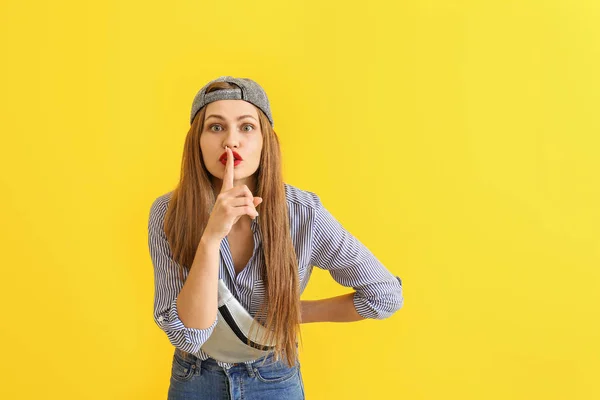 Stilvolle junge Frau zeigt Schweigegeste auf farbigem Hintergrund — Stockfoto