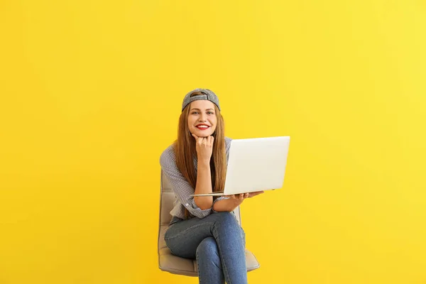 색상 배경에 대한 의자에 앉아 노트북과 행복한 젊은 여자 — 스톡 사진