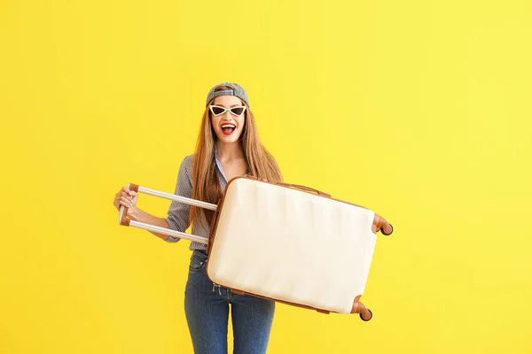 Happy young woman with suitcase on color background — Stock Photo, Image