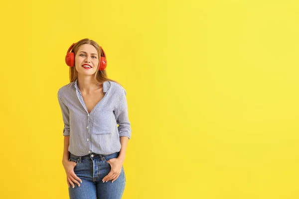 Happy young woman listening to music on color background — Stock Photo, Image