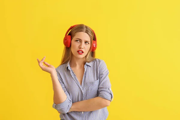 Mujer joven reflexiva escuchando música sobre fondo de color —  Fotos de Stock